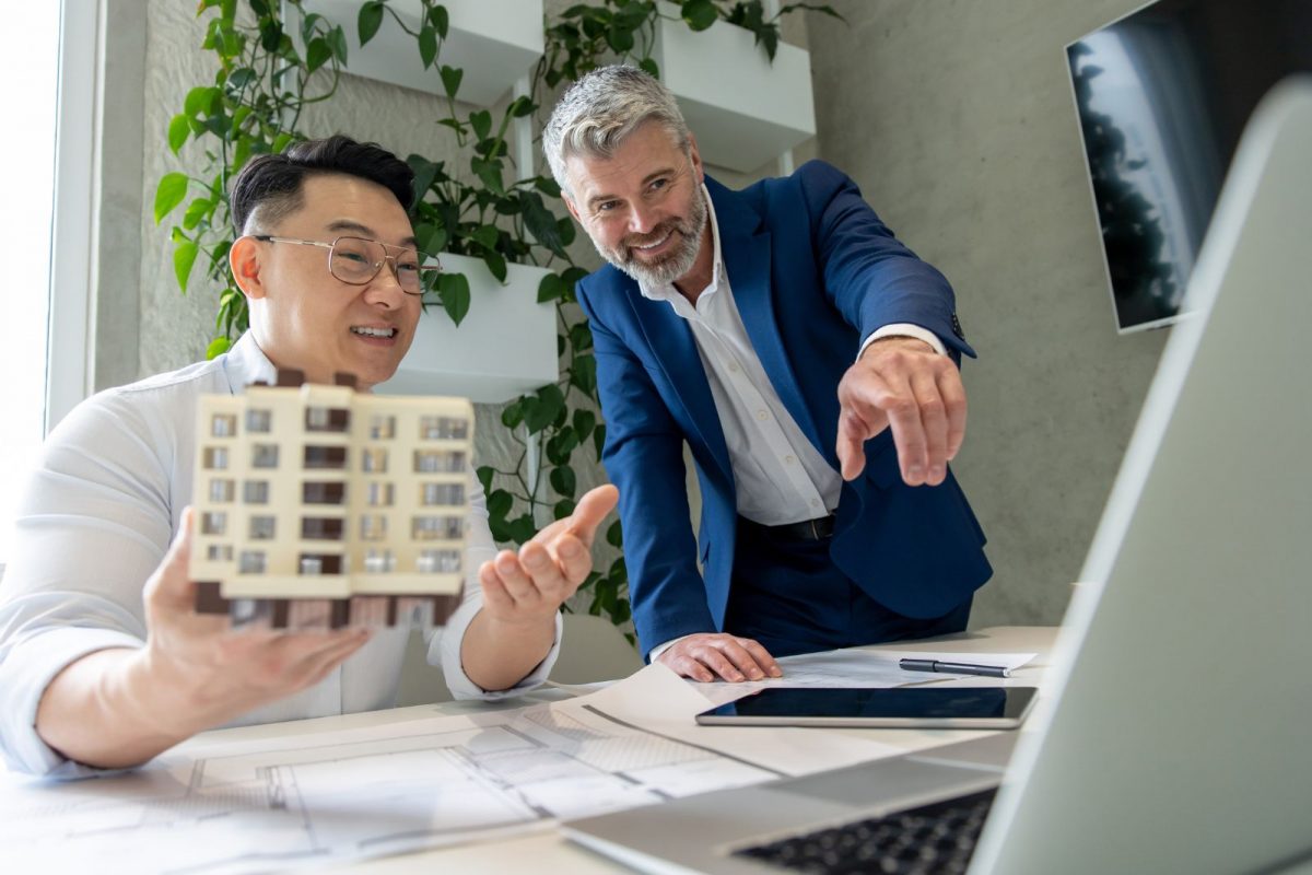 International real estate investors reviewing a property model and discussing US bridge loan financing options for fast property acquisition